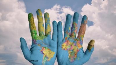 Ilustracja przedstawiająca ręce na których narysowana jest mapa świata